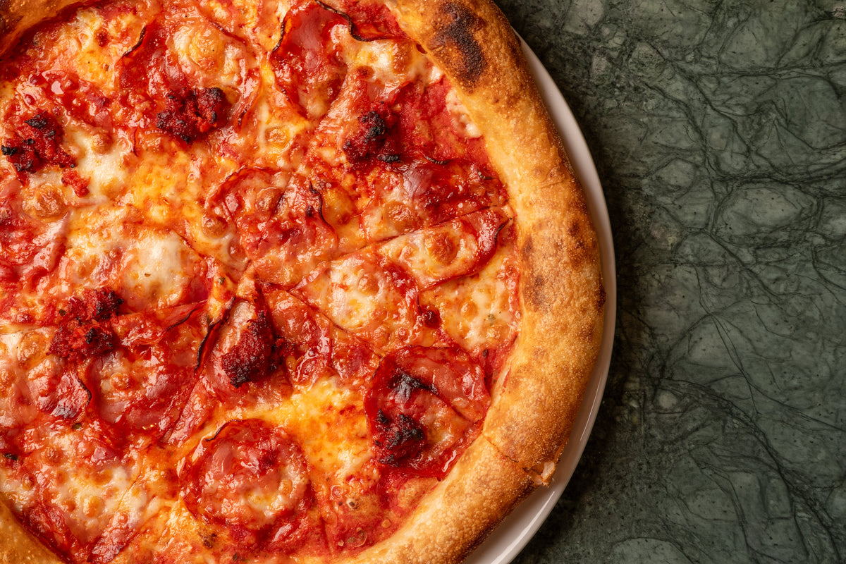 A pepperoni pizza on a green marble table at Fiena, King's Cross