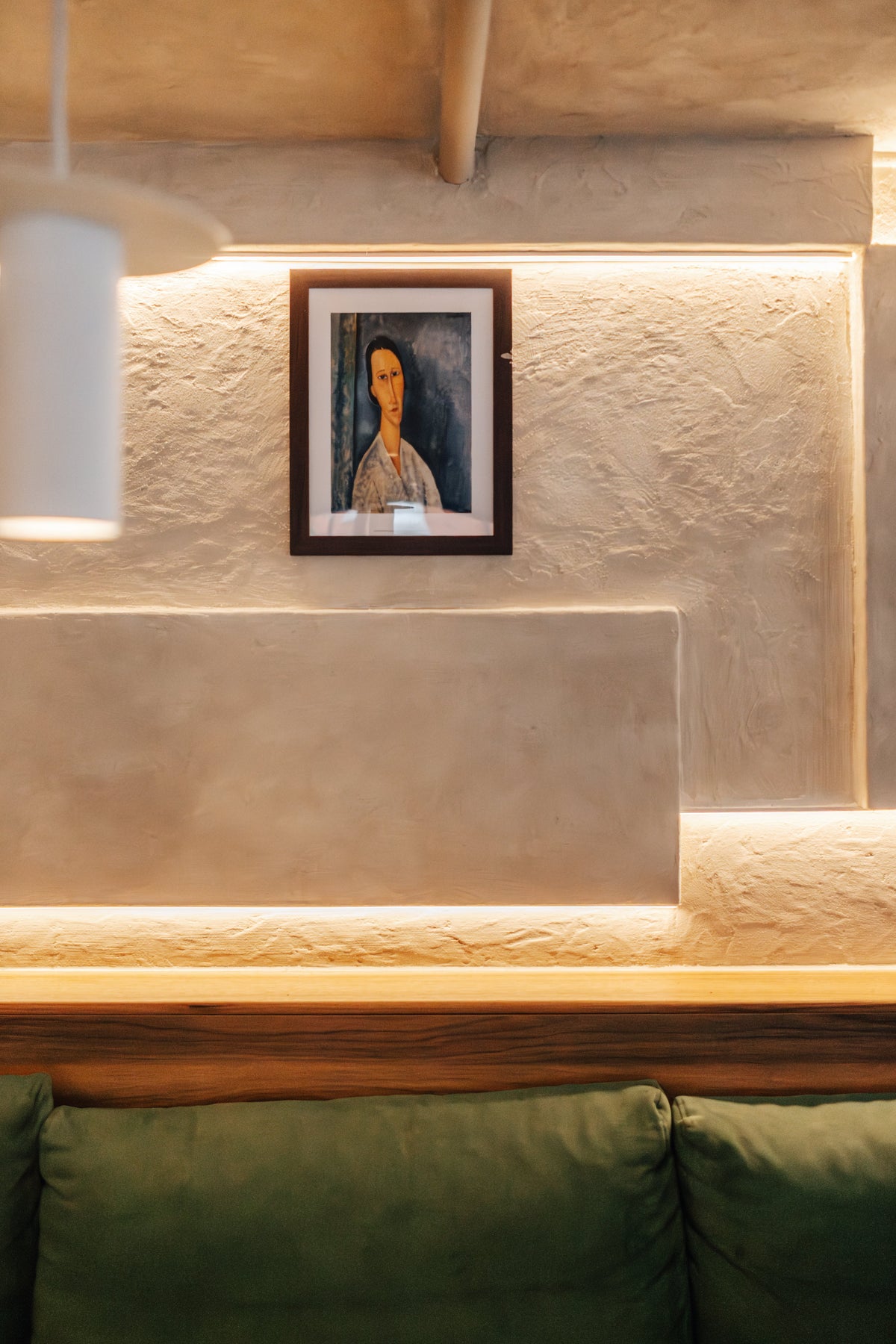 A green banquette beneath a large framed portrait inside Fiena, King's Cross